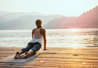A woman is sitting on the dock by the water.