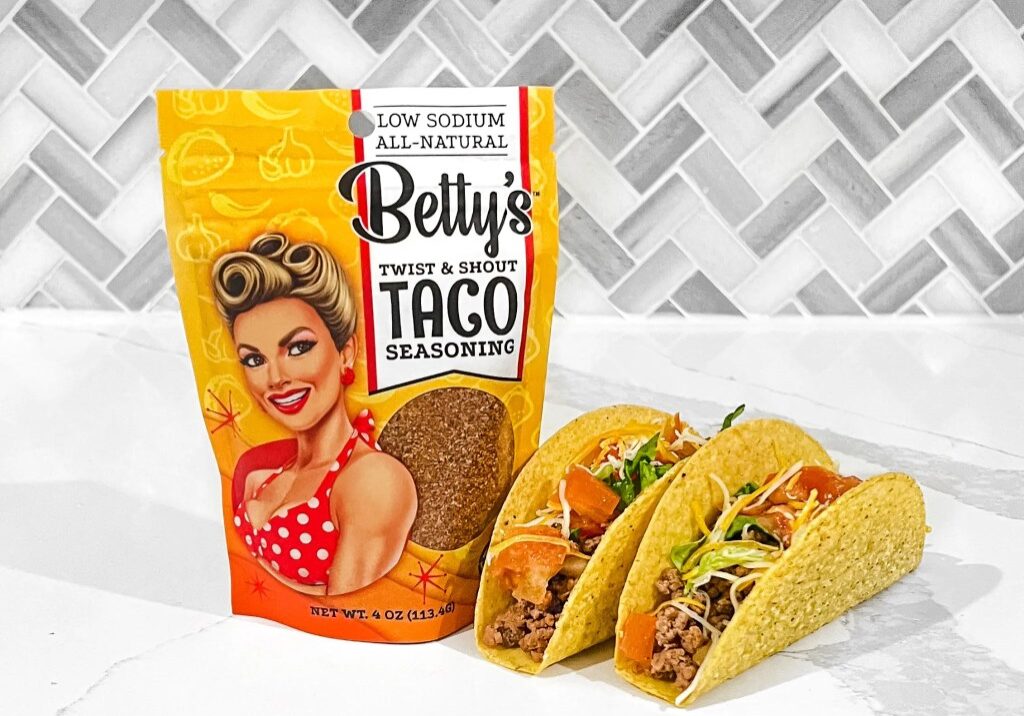 A bag of taco meat and two tacos on the table.