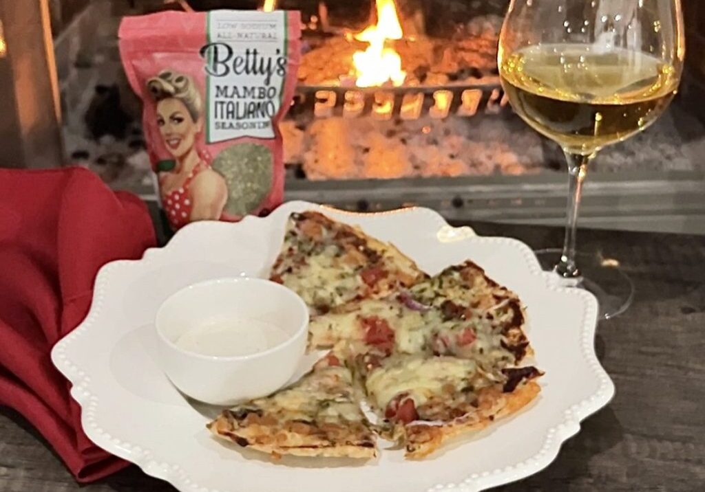 A white plate topped with pizza next to a glass of wine.
