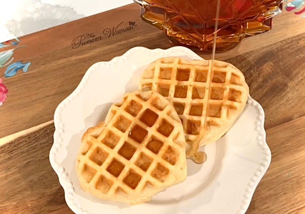 Two waffles on a plate with syrup in the background.